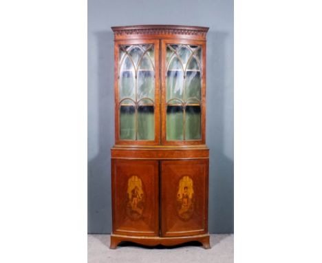 An Edwardian satinwood bow fronted bookcase of "Neo-Classical" design, the upper part with moulded and arcaded cornice, fitte