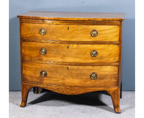 A late Georgian mahogany bow front chest with square edge to top, fitted brushing slide and three long drawers, on shaped apr