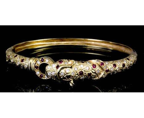 A modern Continental 18k gold ruby and diamond set stiff bracelet, the face modelled in the form of a panther holding a ring 