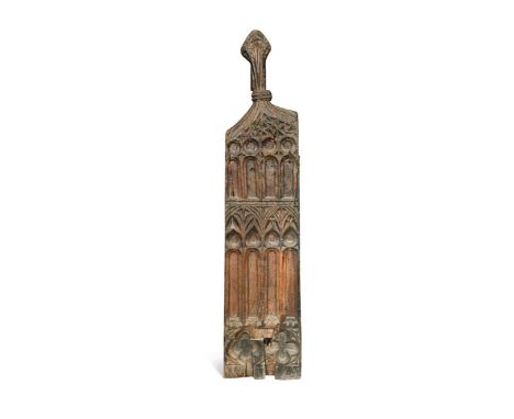 A carved oak pew-end, 16th century, the poppy-head finial with losses, the end decorated with carved sunk tracery of slender 