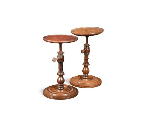 A near pair of  mahogany candle stands, early 19th century, the circular tops with height adjustable stems, raised on turned 