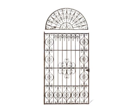 A wrought iron country house gate, possibly late 18th century, the rectangular gate with demi-lune pediment decorated with sc