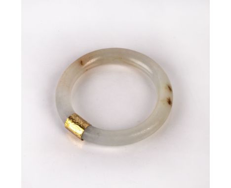 Jadeite bangle Burmese with a yellow metal mount, 7.5cm across Condition: general wear, (untested for treatments)