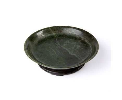 Nephrite jade shallow dish Chinese, 19th Century the dish with raised rim, on a hardwood stand, 25cm x 4.5cm Condition: natur