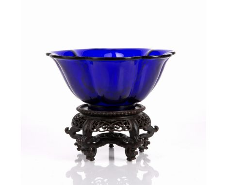Peking blue glass bowl Chinese, 19th Century of lotus form, with a carved hardwood stand, 21.5cm high x 9.25cm high Condition