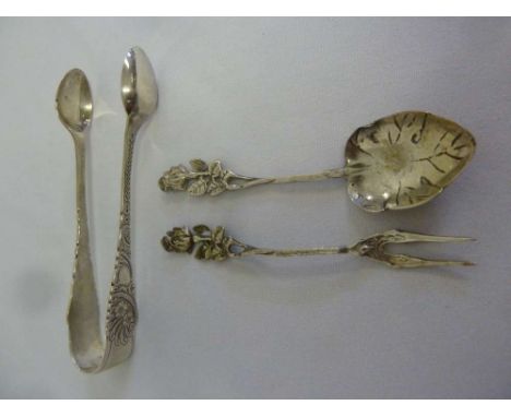 A pair of silver tongs and a white metal spoon and fork