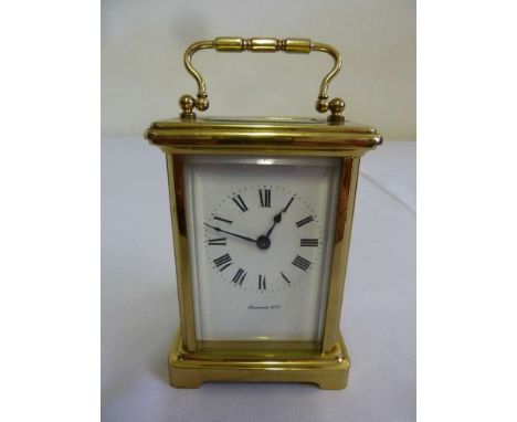 A brass carriage clock of customary form retailed by Harrods