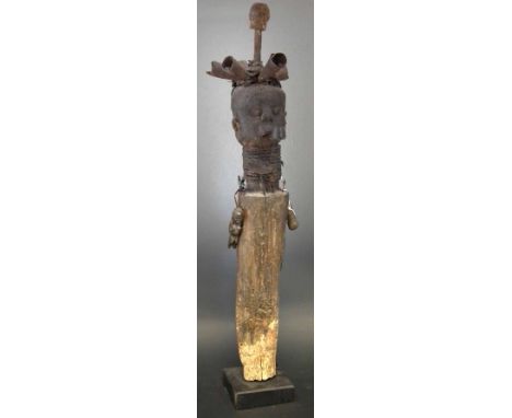 Figural post, applied with metal bells a pipe and a small cymbal, two small wood figures hang to either side. 97cm high     A