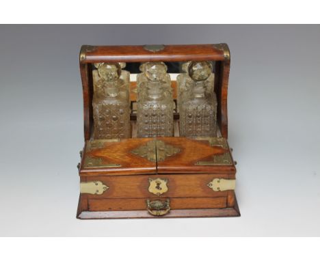 A LARGE LATE 19TH CENTURY OAK THREE DECANTER TANTALUS, the tantalus with a mirror back, three hobnailed cut decanters, twin h