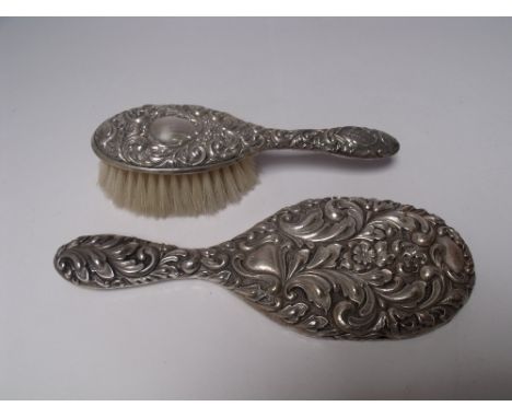 A SILVER BACKED HAND MIRROR - BIRMINGHAM 1901, together with a silver backed child's hairbrush, both with embossed decoration