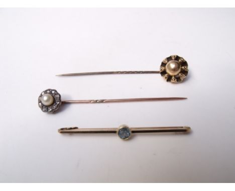 A 15CT GOLD BAR BROOCH SET WITH A PALE BLUE TOPAZ, together with two yellow metal stick pins (3) Buyers - for shipping pricin