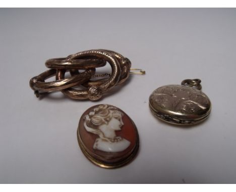 A VICTORIAN PINCHBECK 'KNOT' BROOCH, together with a yellow metal locket pendant - scrolling foliate decoration to both sides