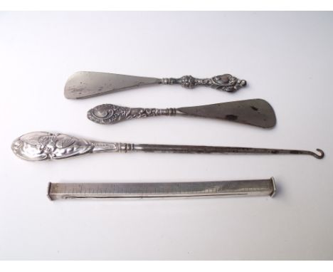 A HALLMARKED SILVER HANDLED BUTTON HOOK - BIRMINGHAM 1906, embossed cherubic decoration to the handle, together with two silv