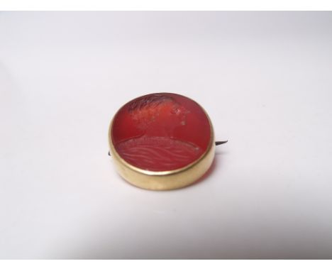 A CARVED INTAGLIO CARNELIAN BROOCH, carved portrait of Julius Caesar set in an oval yellow metal frame, H 2.6 cm Buyers - for
