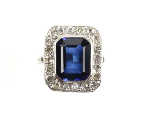 Synthetic sapphire and diamond ring, central rectangular step cut sapphire 12.4 x 9.7mm, set with in a frame of old cut and t