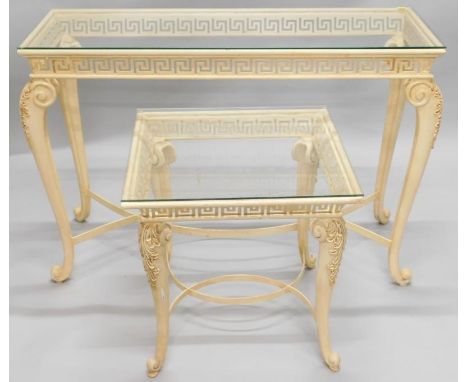 A cream and gilt painted console table, with a glass top, a pierced Greek key frieze on cabriole legs, and central intertwine