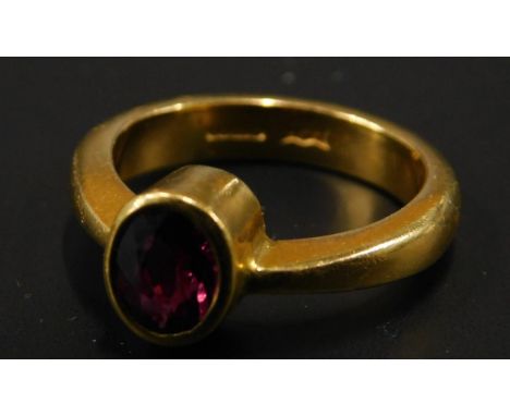 A 22ct gold dress ring, set with oval cut ruby in rub over setting, maker H.W.F, 8.9g all in. 