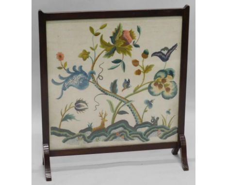 An Edwardian mahogany fire screen, with a crewelwork panel depicting animals, butterflies, flowers etc., 60cm wide