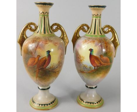 A pair of Royal Crown Devon two handled porcelain vases, each decorated with pheasants by J Coleman, in the manner of Royal W