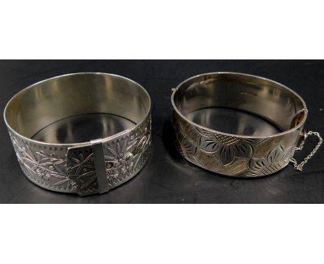 Two silver bangles, to include a floral design bracelet and an exotic flower and leaf bangle, 87.3g all in. 