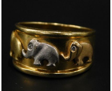 An elephant dress ring, with tri-colour graduated elephants, set with tiny diamond eyes, on a yellow metal band, marked 750, 