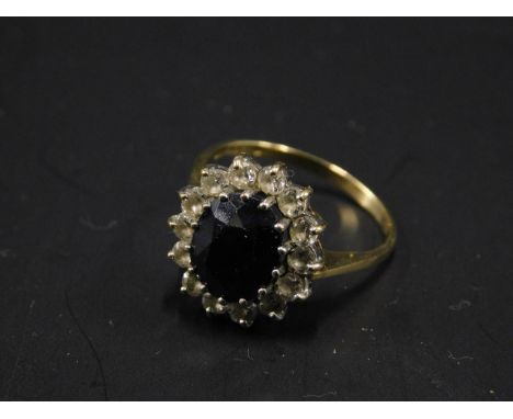 A 9ct gold dress ring, in a floral cluster, with central blue stone, surrounded by white stones, 3.3g all in. 