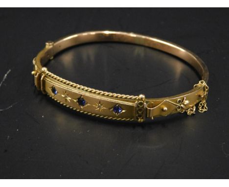 A Victorian bangle, set with three sapphires and two diamonds, with elaborate design, yellow metal, unmarked, 9.7g all in. 