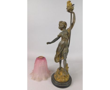 A late 19thC French gilt spelter table lamp, modelled in the form of a female figure holding a torch, with a cranberry tinted
