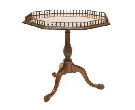 A George III mahogany tripod table, the octagonal top with a turned gallery and carved border, on a baluster column with carv