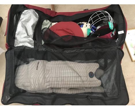 A CRICKET BAG AND CONTENTS TO INCLUDE PADS, HELMET, GLOVES, HAT, BALLS ETC 