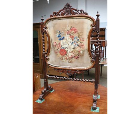 A Victorian Rosewood Firescreen, with a needlework panel and barley-twist supports, 74cm by 124cm
