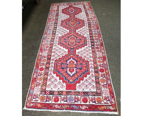 A North West Persian Runner, the pale camel ground with a column of linked medallions, enclosed by borders of stylised rosett