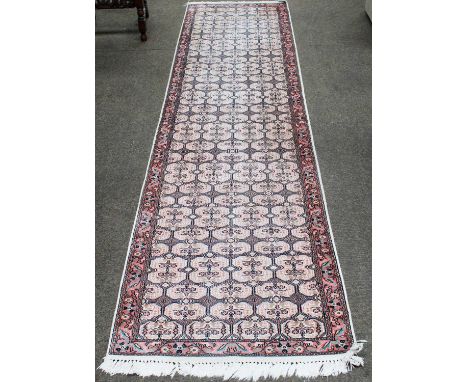 A Kashmir Silk Piled Runner, the ivory lattice field of floral design enclosed by narrow salmon pink borders, 302cm by 79cm