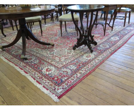 An Indian carpet, the blue and ivory medallion on a red field filled with flowers and ribbons, within ivory spandrals and mul