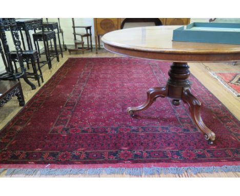 An Afghan carpet, with all over flowerhead pattern on a red ground within a multiple border, 300 x 196cm  