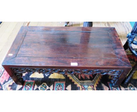 A Chinese rosewood opium table, the rectangular top over a pierced scroll carved frieze and brackets on square legs and scrol