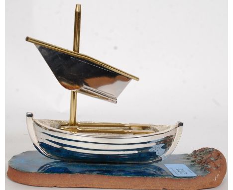 A polished steel / chrome decorative rowing boat ship displayed on a glazed sea affect tile marked Albert