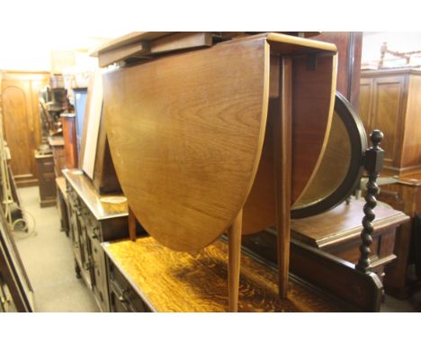 A vintage retro 1970's teak wood drop leaf dining table. The leaves raised on gate leg supports