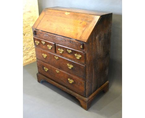 A George III Oak Bureau, the fall front enclosing a fitted interior with well above two short and two long drawers with brass