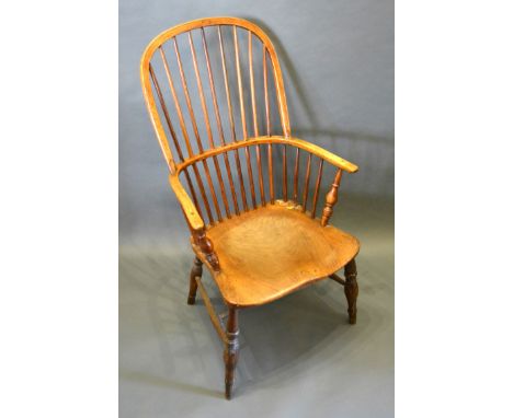 An Early 19th Century Elm Windsor Armchair, the shaped stick back above a panel seat raised upon turned legs with stretchers 