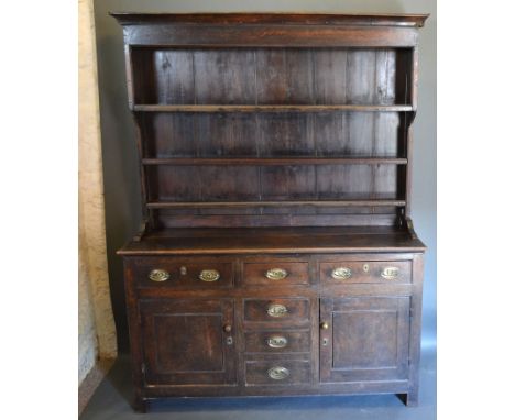 A George III Oak Dresser, the boarded shelf back above three frieze drawers and central simulated drawer flanked by cupboards