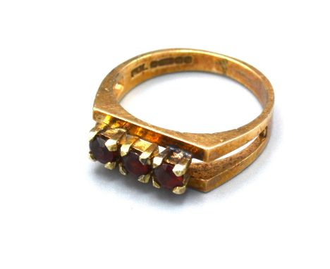 A 9ct Yellow Gold Dress Ring set with three garnets within a pierced setting, 3.3 gms Size K 