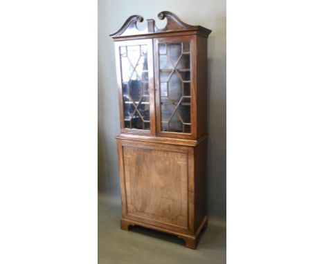 A 19th Century Mahogany Bookcase with a swan neck pediment above two astragal glazed doors enclosing shelves, the lower secti