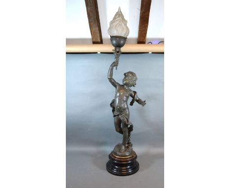 A Patinated Spelter Table Lamp in the form of Putti holding a torch with opaque glass shade 101 cms high 