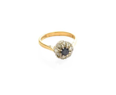 An 18 Carat Gold Sapphire and Diamond Cluster Ring, the round cut sapphire within a border of eight-cut diamonds, in white cl