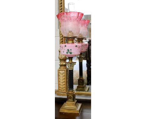 A Victorian Brass Corinthian Column Based Oil Lamp, with painted opaque pink glass reservoir and cranberry tinted etched glas