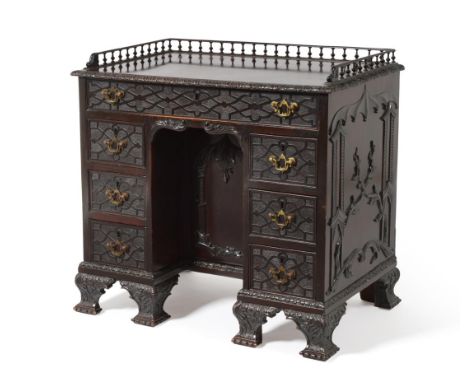 A Mahogany Kneehole Desk, in the Chippendale Gothic style, with a spindled gallery, seven drawers about the kneehole cupboard