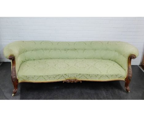 A Victorian sofa, with pale green upholstered back arms and seat on carved cabriole supports, terminating on ceramic castors,