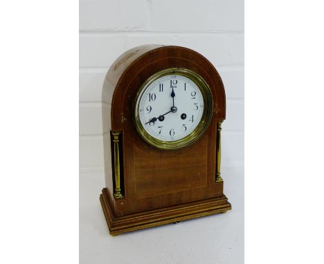 A mahogany and inlaid mantle clock, the enamel dial with Arabic numerals flanked by brass pilasters on a plinth base, 31cm hi