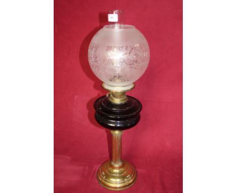 A Victorian brass oil lamp with coloured glass oil reservoir and decorative glass shade